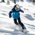 Monitrice réalisant un virage en snowboard hors-piste à Vars et Risoul