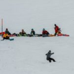 Enfants observant leur monitrice réaliser un exercice pendant un cours collectif de snowboard